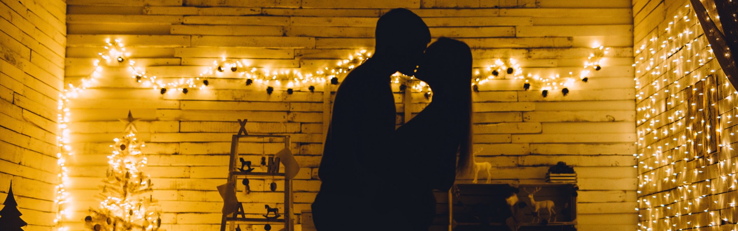 couple kissing in living room with string lights