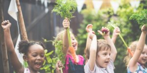 four children smiling holding vegetables