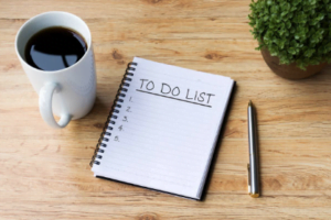to-do list, pen, and coffee on a wooden table
