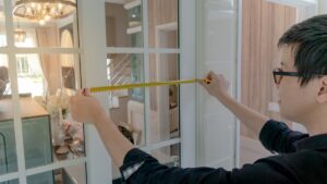 man measuring the width of a window