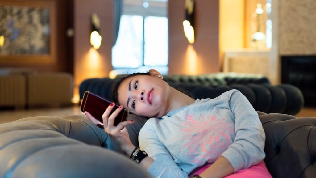 woman sitting on couch looking at phone