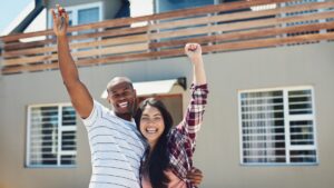 couple smiling holding their house keys outside of their new home