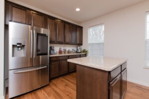 simple kitchen with dark wooden cabinets and a stainless steal fridge