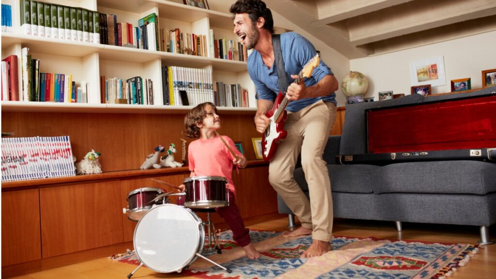 father playing guitar while son plays the drums