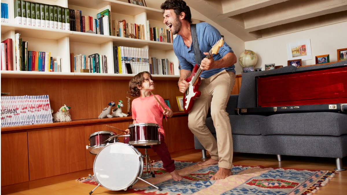 father playing guitar while son plays the drums