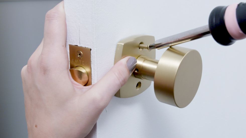 person installing gold doorknob