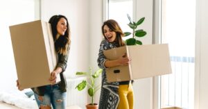 two women carrying moving boxes