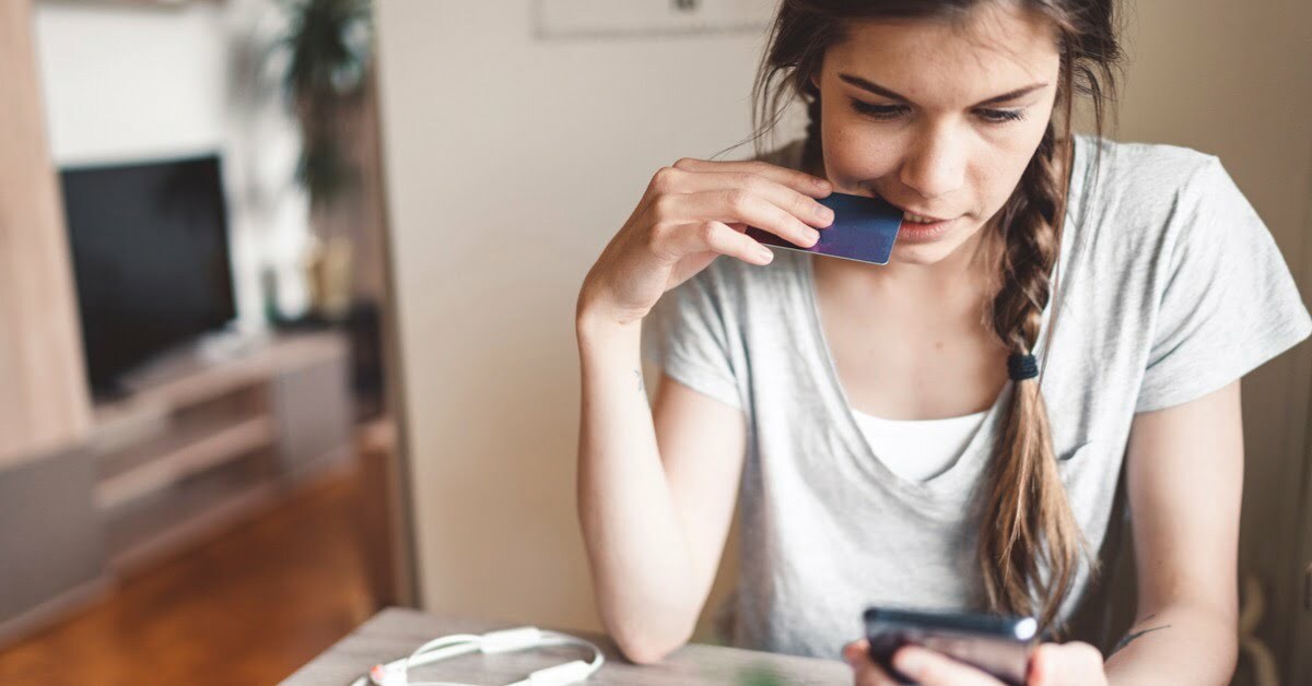 woman looking at phone holding credit card