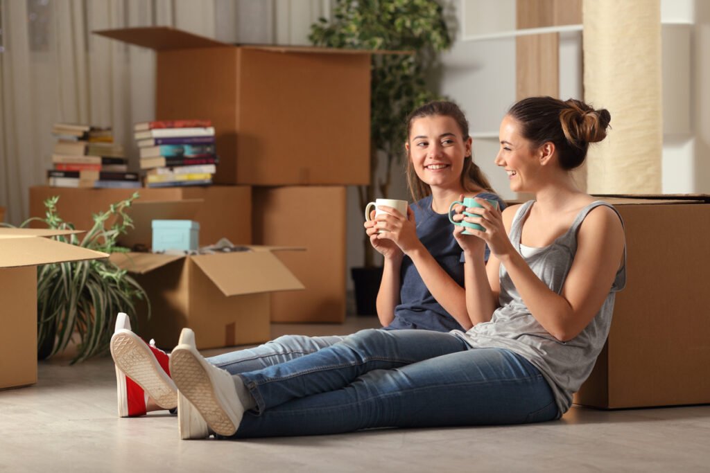 two women sitting with moving boxes