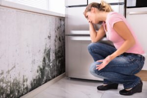 woman looking at mold on wall