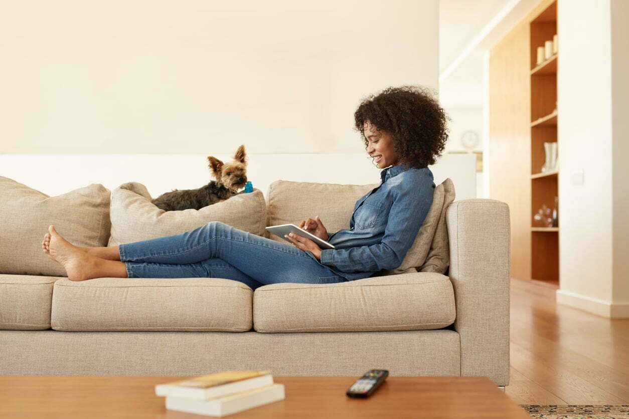 woman on couch with dog and iPad