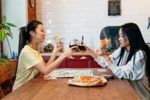 two women drinking wine and eating pizza