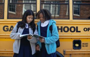 two kids standing outside school bus