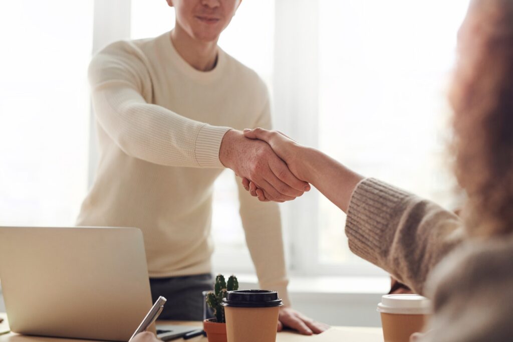 two people shaking hands over desk