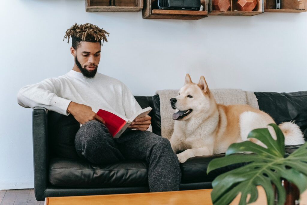 man and dog sitting on couch