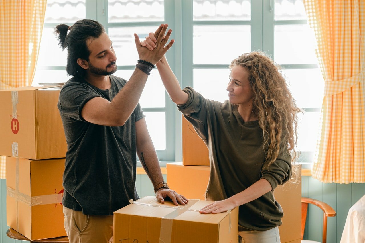 couple with moving boxes high fiving