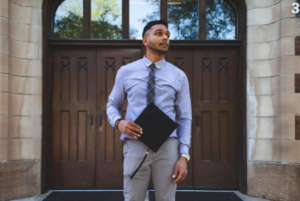 man standing holding a graduation cap