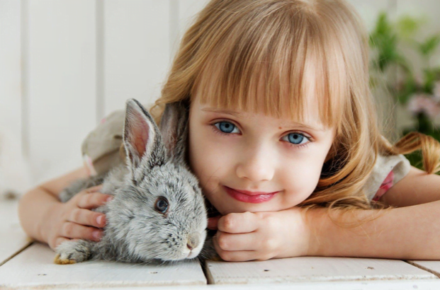 child smiling next to a rabbit