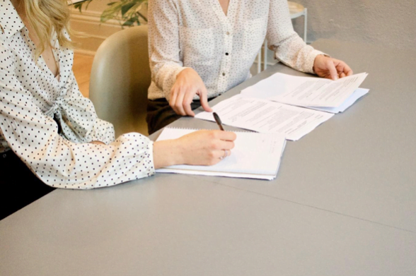 two women at desk signing papers