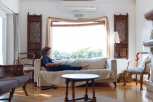 woman sitting on couch in her living room and typing on laptop