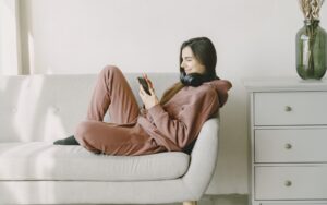 Renter relaxing on a sofa, checking her phone to see how much rent can I afford and the right rent price to pay rent.