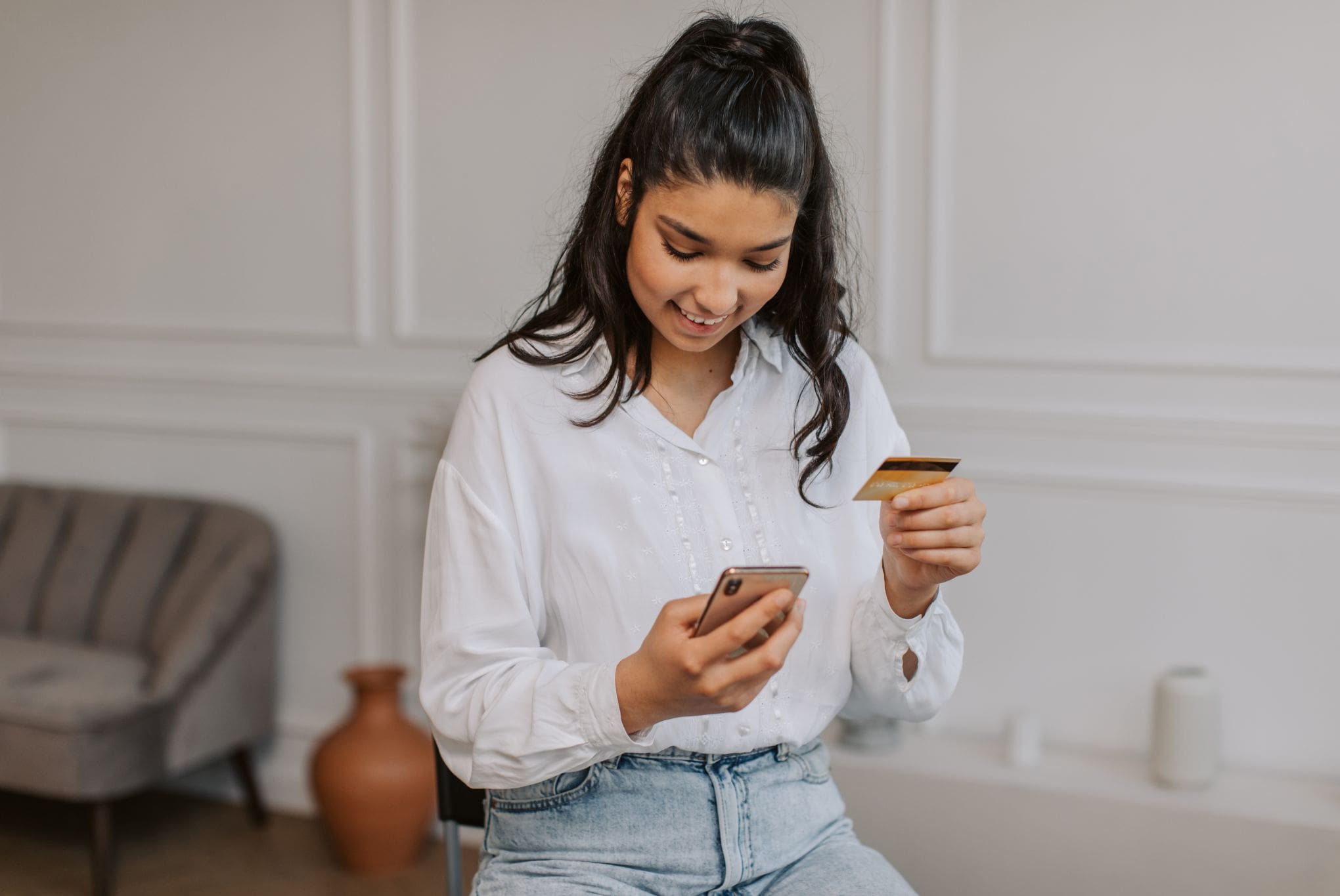 Young woman paying rent online using a smartphone and credit card
