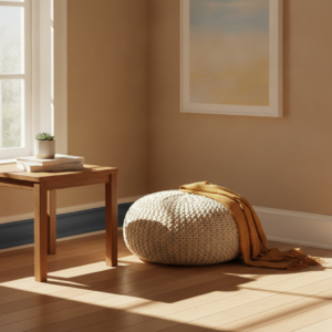 A sunlit living room corner with a wooden table, succulent, and a cream-colored ottoman draped with a mustard yellow throw blanket, showing an example of a rabbit proof apartment.